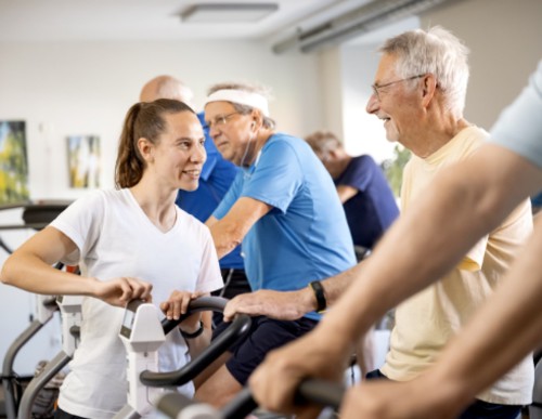 Ältere Männer beim Kardiotraining unter Anleitung einer Trainerin